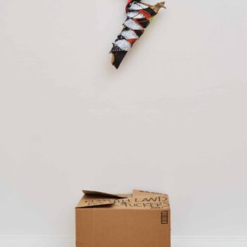 Natalie Ball, Klamath Land Back Fuckers, 2021, Boot Leg Fire charred wood, deer rawhide, Converse, braiding hair, paint, textiles, cardboard box; Sculpture: 24 x 14 x 5.5 in., Box: 18 x 22 x 12”. Museum Purchase from the Eiteljorg Contemporary Art Fellowship. Image courtesy by the artist and Bortolami Gallery, New York. Photographer: Guang Xu